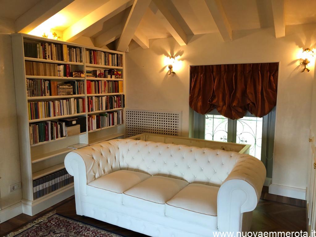 Zona lettura con libreria bianca di design e divano..