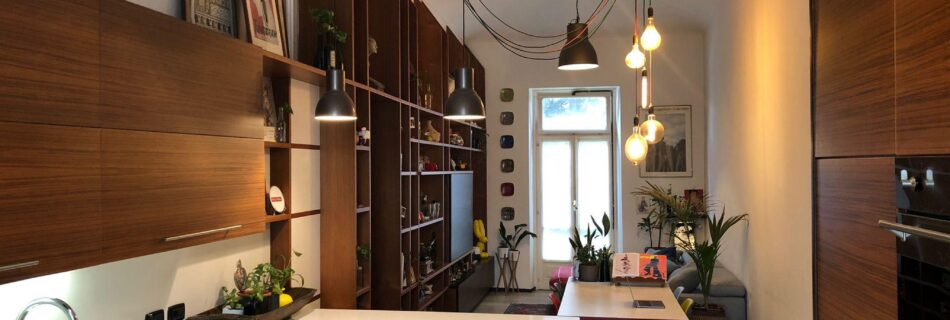 Open space zona living con cucina e libreria in legno teak.