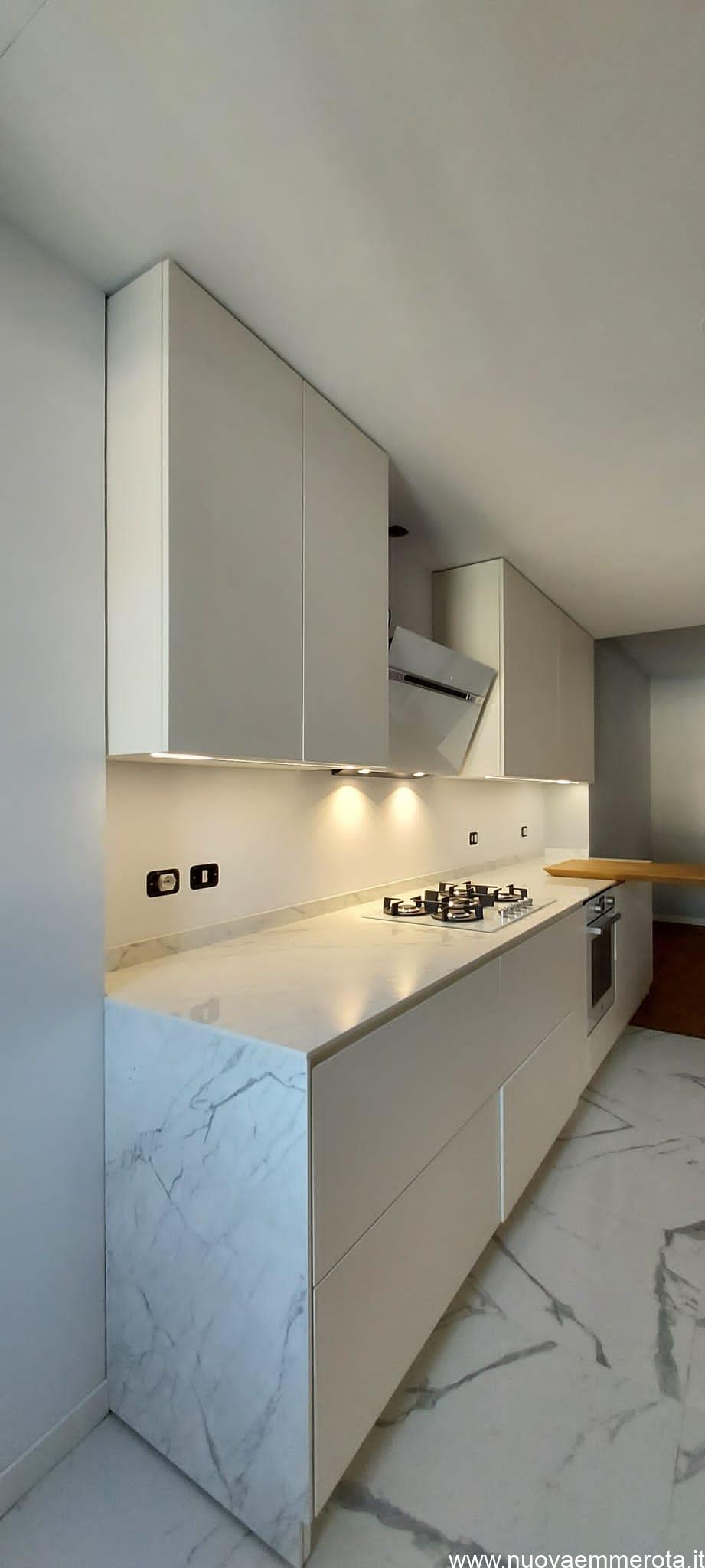 Cucina laccata bianca con profili in marmo.